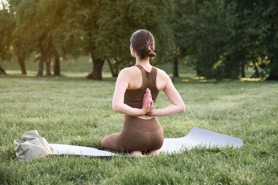 A young positive woman in a gymnastic suit practices yoga