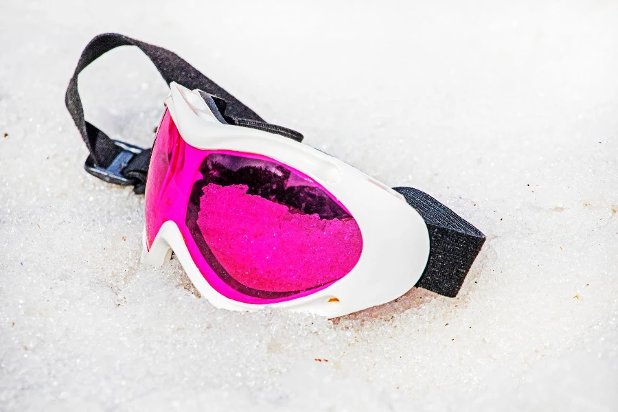 pink lying mask lies on a wet snowy slope on a sunny day