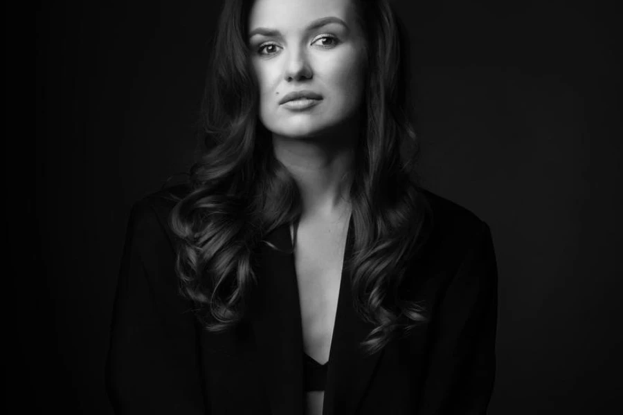 Portrait of beautiful woman with black suit and big wavy hair in dark studio background