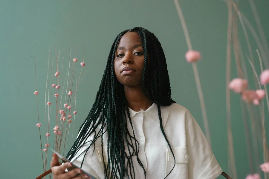 Confident young African American lady looking at camera against green wall