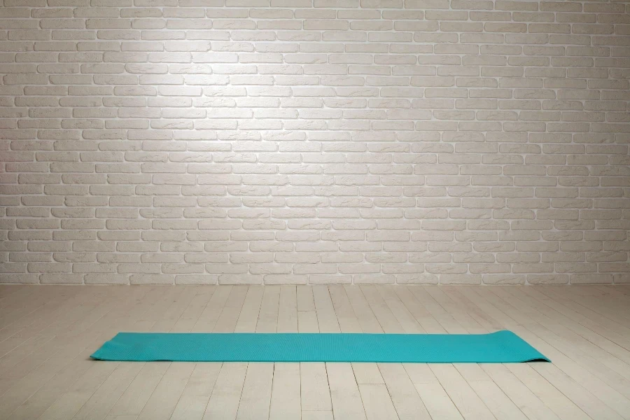 Fondo de habitación vacía, piso de madera, pared de ladrillo blanco con colchoneta de fitness