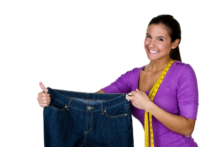 cute woman with a happy expression holding up a denim skirt