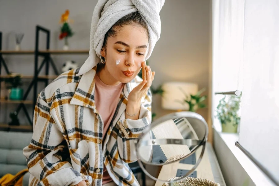 a beautiful young woman sitting in the living room applying face cream