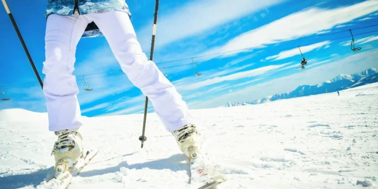 Close up woman skier bright bottom view of ski boots and skis while stop on carving in fast motion