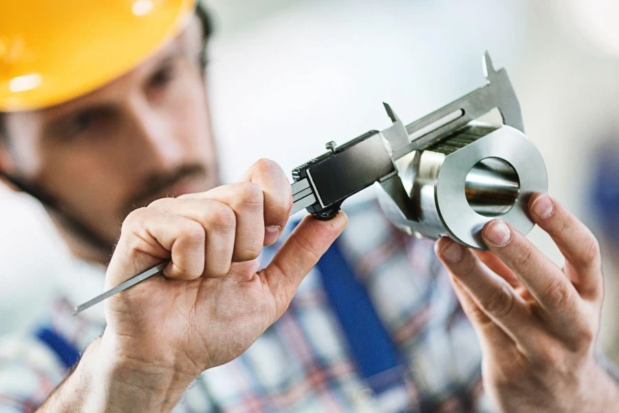 Closeup of metal processing plant worker inspecting certain pieces of finished products.