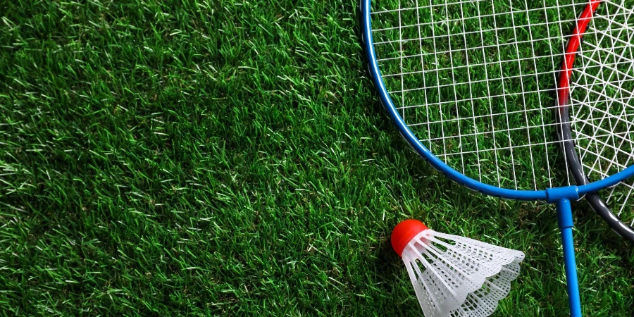 Duas raquetes de badminton e petecas na grama verde