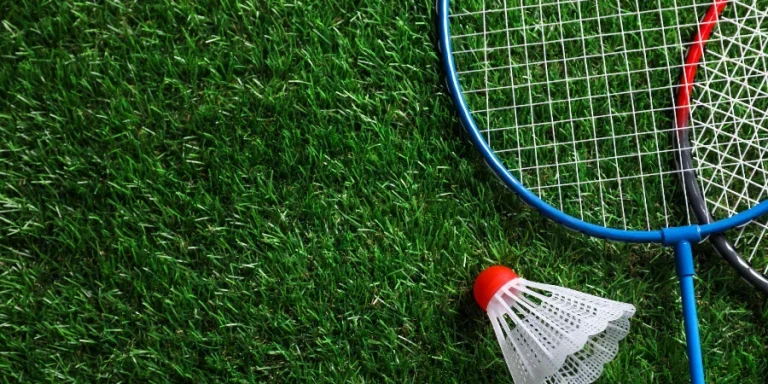 Two badminton rackets and shuttlecock on green grass