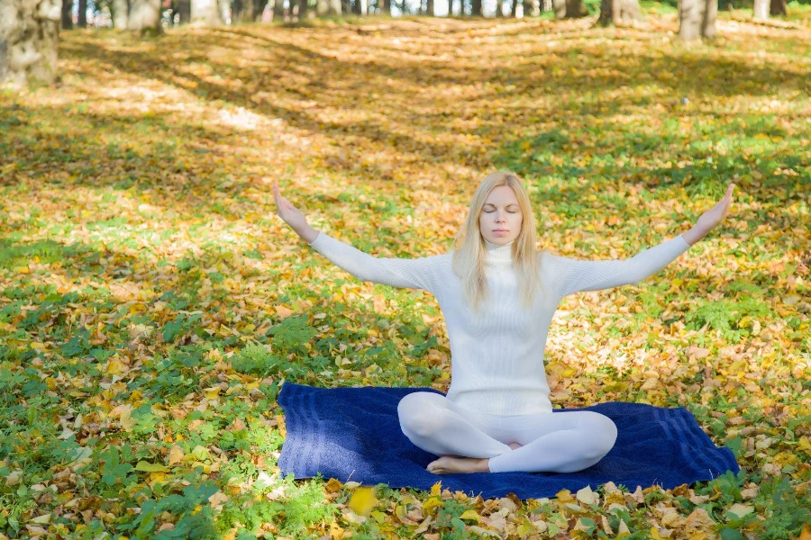 In autumn day young woman practicing yoga in the park atmosphere