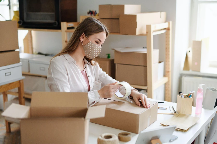 Young woman dropshipper working at home, packing parcels.