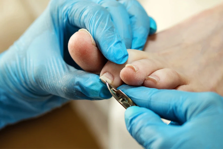 Tecnico delle unghie che taglia le unghie dei piedi del cliente
