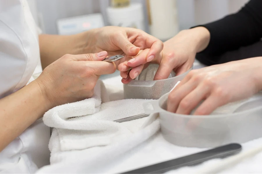 Nageltechniker pflegt die Nägel einer Kundin