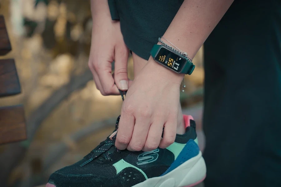 Person, die einen Fitness-Tracker trägt und ihre Schuhe bindet