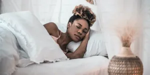 Frau schläft im Bett, der Kopf ruht auf einem dicken Kissen