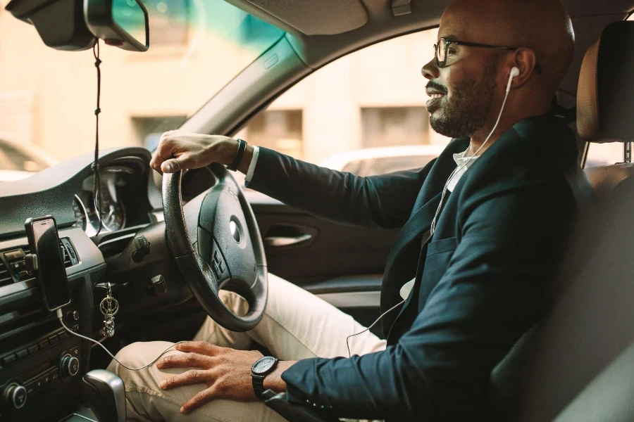 jeune homme en costume passant un appel en conduisant une voiture