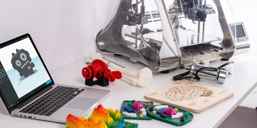3D printer on desk with laptop and 3D-printed items