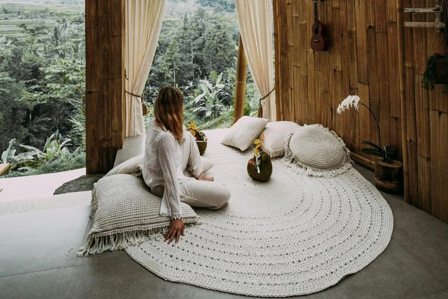 A person sitting on a white knitted round mat