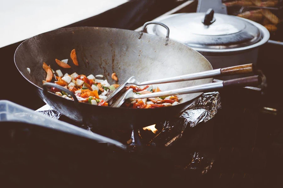 A stir-fry pan with vegetables and two spoons