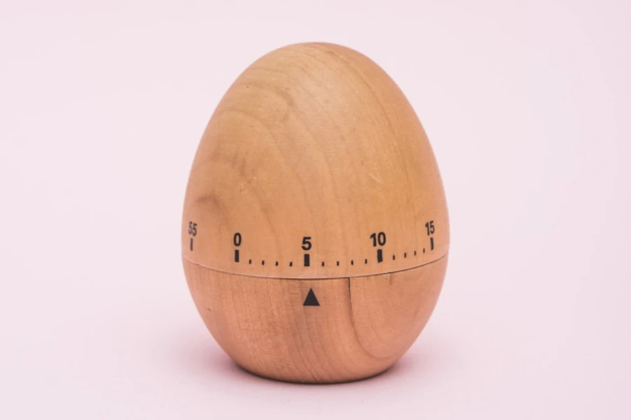 A wooden egg timer on a pink background