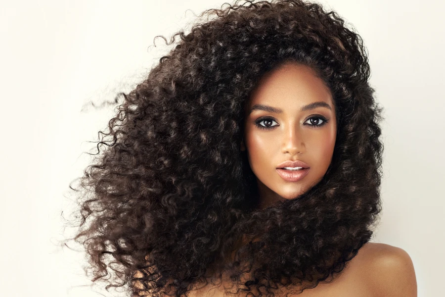 Big black eyed gorgeous young model is demonstrating long dense curly hair