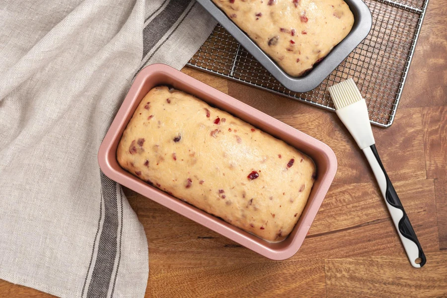 Bread dough with cranberry in pink and gray loaf pans