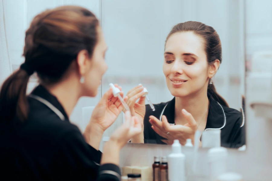 Cheerful lady applying a rejuvenating treatment fighting wrinkles