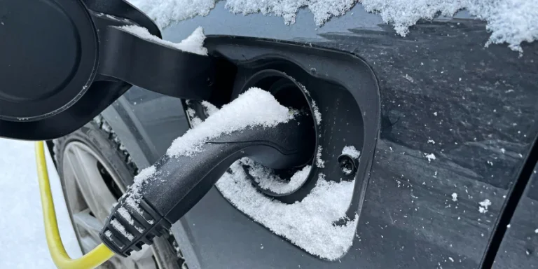 Close up of charging electric car in the winter with snow outside