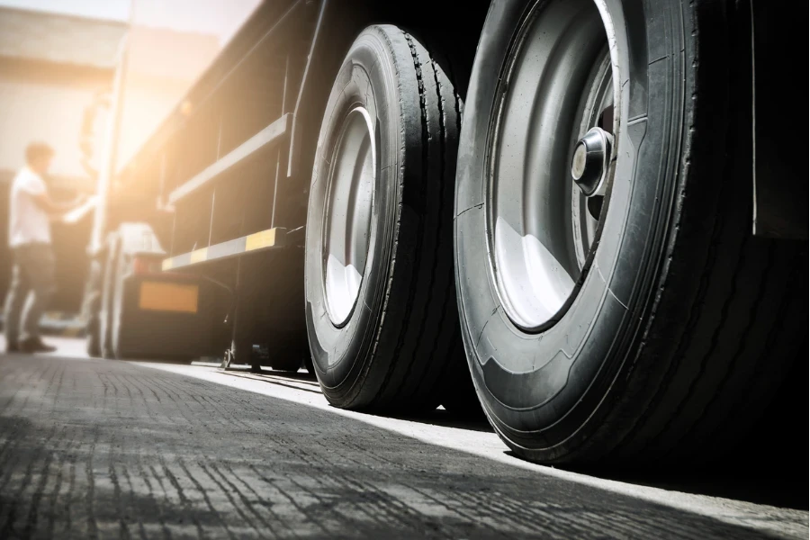 Close up truck tire and truck driver is checking safety around of semi truck