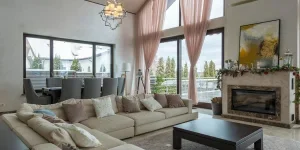 Comfortable lounge zone with soft furniture against fireplace near huge windows in villa