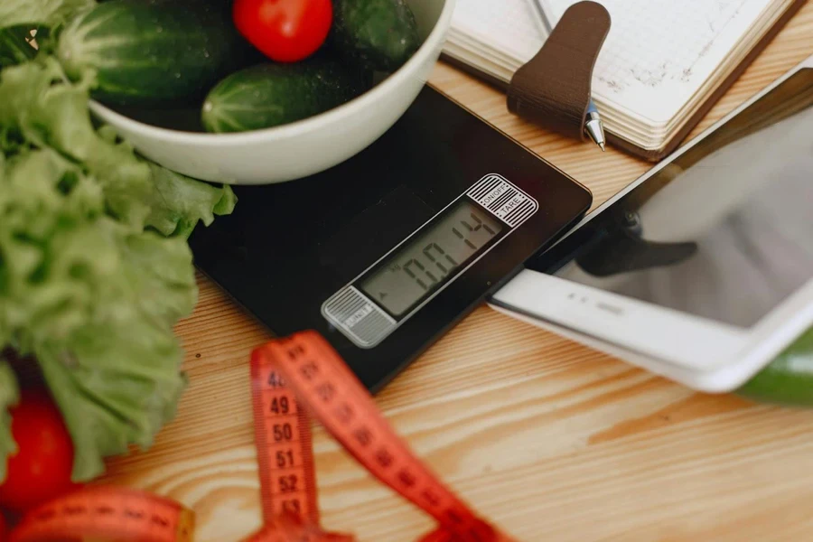 Cucumber and tomatoes placed on a kitchen weighing scale