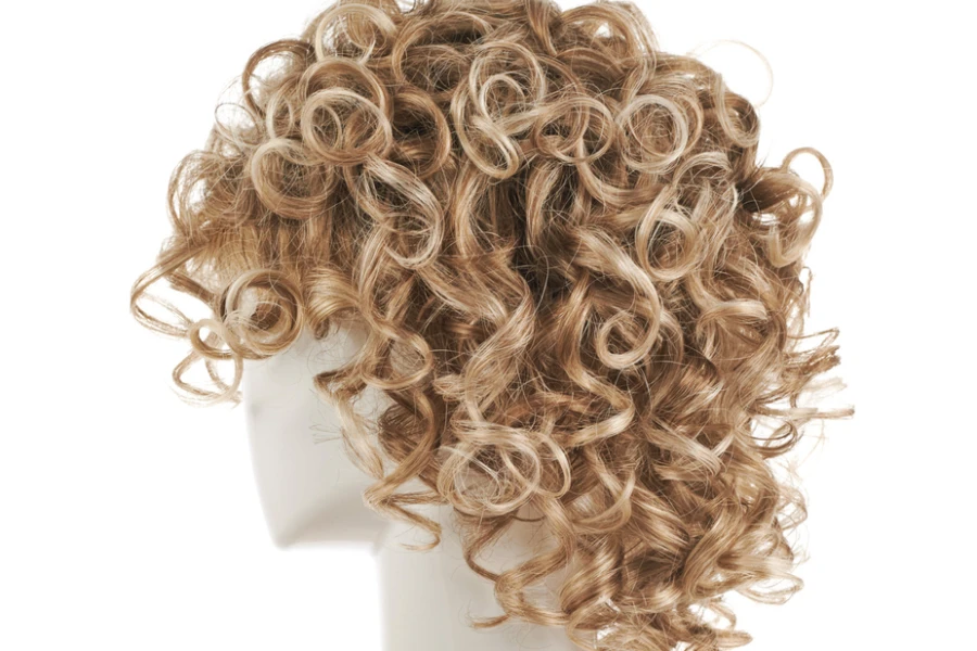 Curly hair wig over the white plastic mannequin head isolated over the white background
