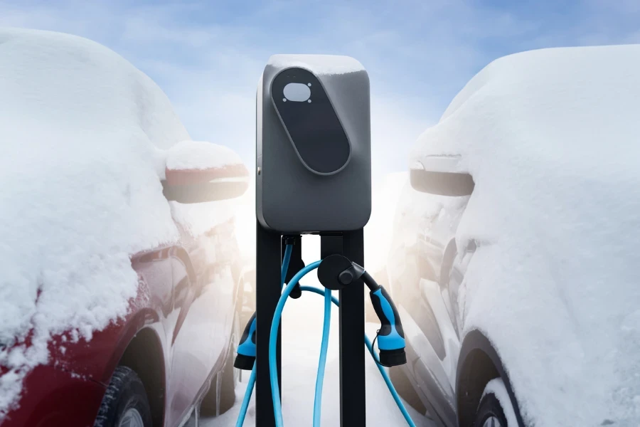 Electric car charging station on a background of snow covered winter cars