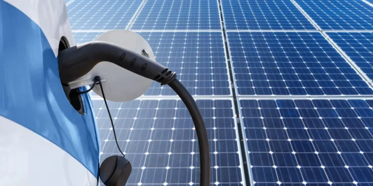 Electric car with a connected charging cable on the background of solar panels