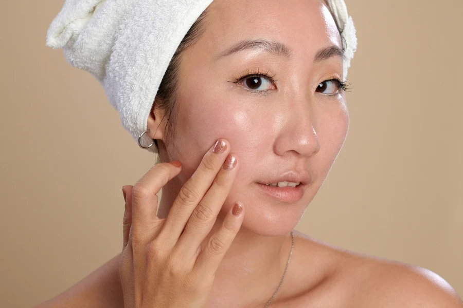 Face of young woman touching her flawless skin after morning shower