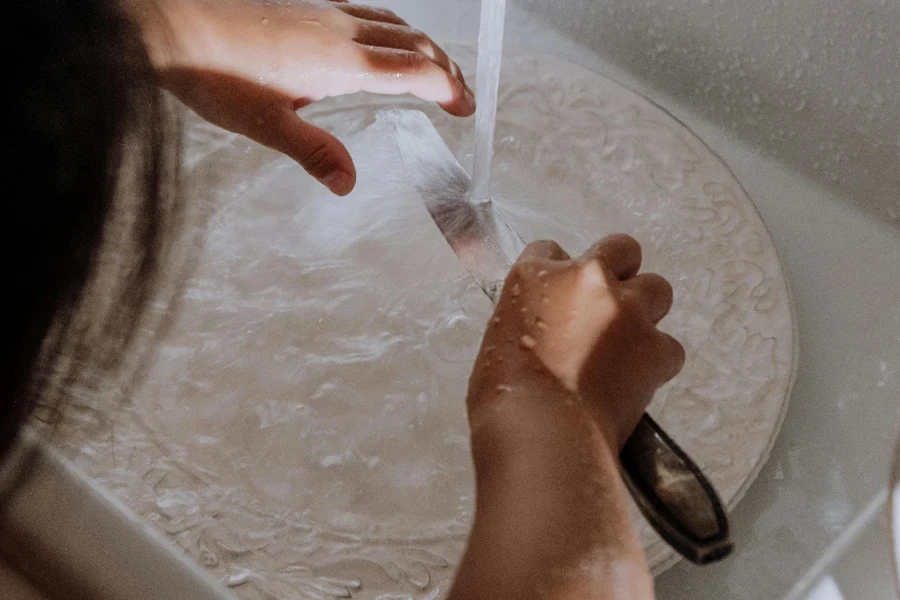 Girl washing knife and plate in sink