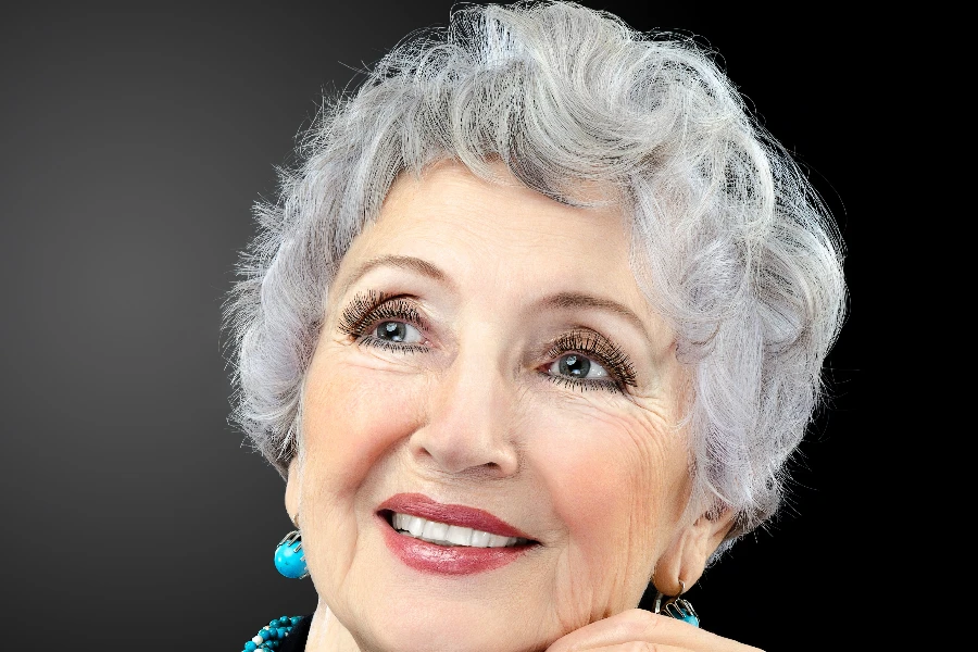 Grey haired spectacular 76-year-old woman posing on black background