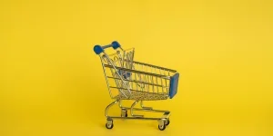 Isolated shining metal shopping trolley without anything located separately on yellow background