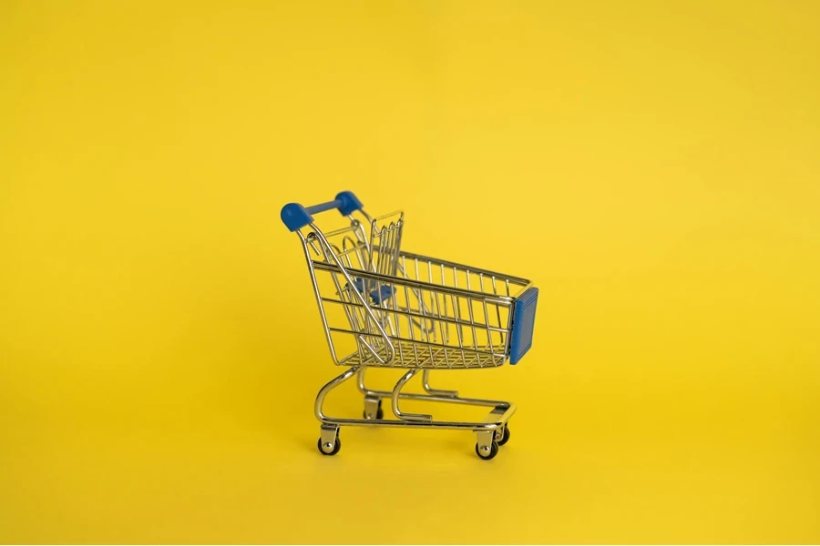 Isolated shining metal shopping trolley without anything located separately on yellow background