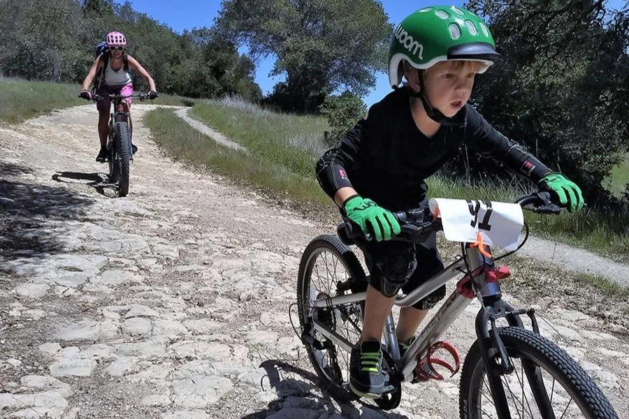 Kid racing down the road in green gloves and helmets