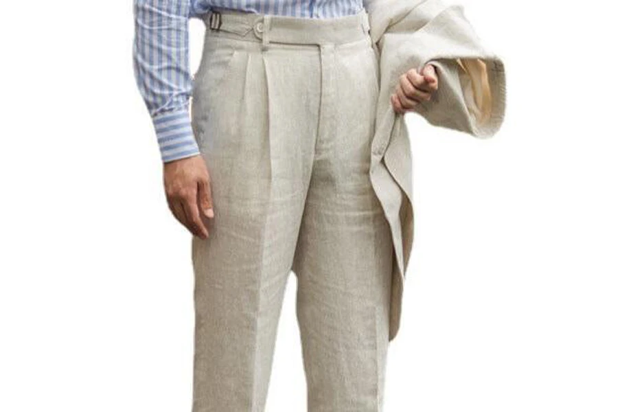 Man holding a blazer while wearing pleated linen pants