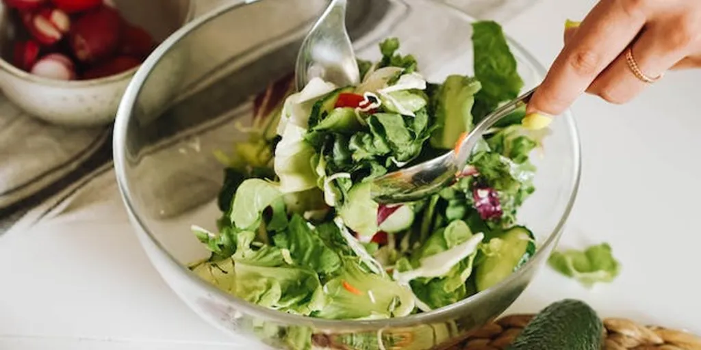 Person preparing salad in a bowl