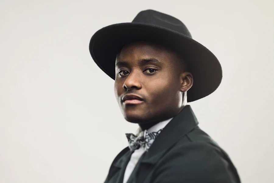 Portrait of african american man standing with his arms crossed in black jacket and hat