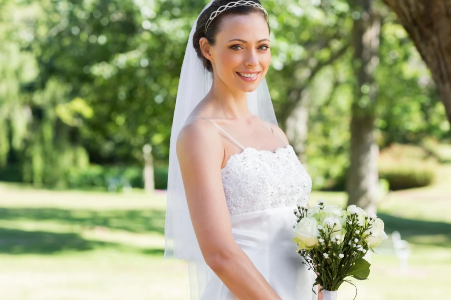 Portrait of bride with flower bouquet standing in garden