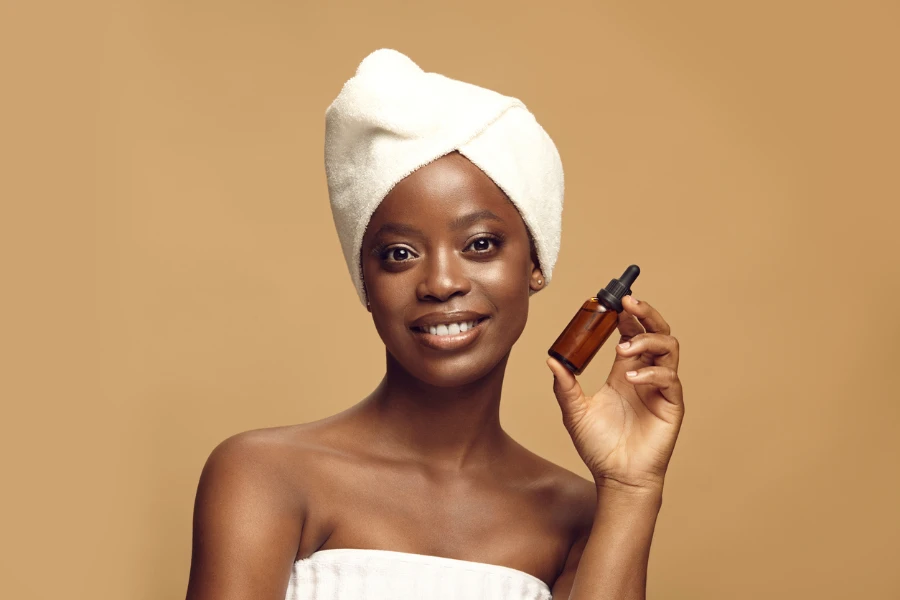 Smiling african american girl after spa procedures preparing apply cosmetic products for skin care