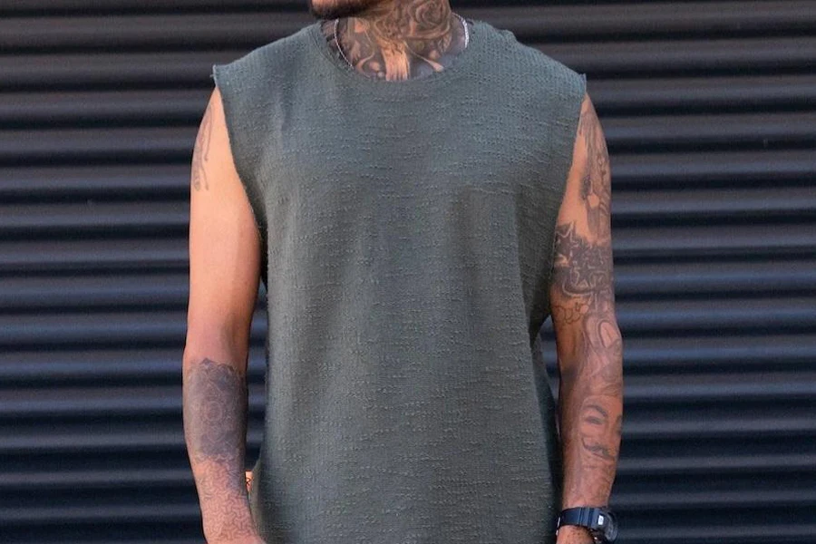 Tattooed man wearing a gray oversized tank top