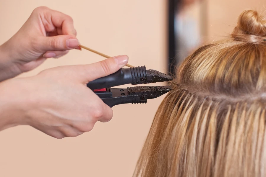 The hairdresser does hair extensions to a young girl