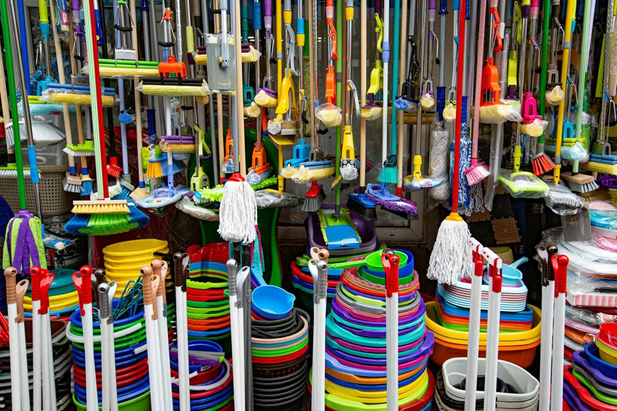 Various colorful mops and brushes arranged with stack of plastic basins and bins
