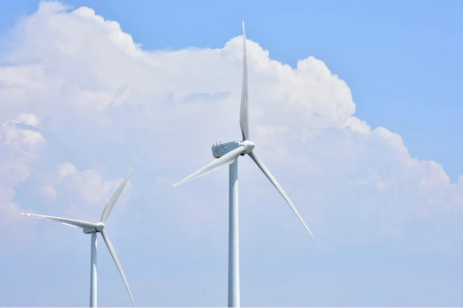 White wind turbine under clouds and a blue sky