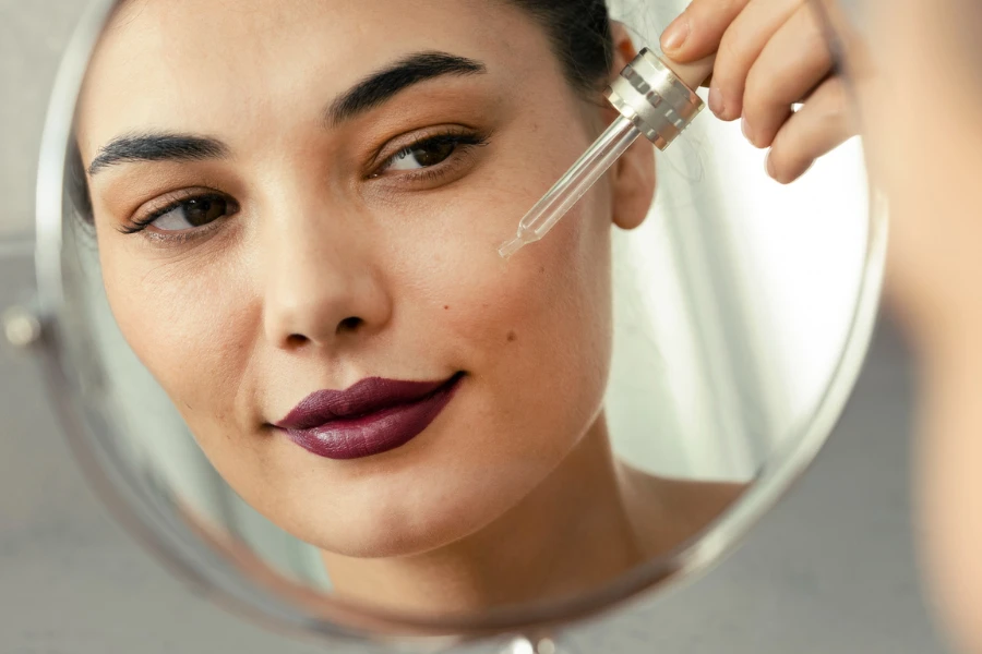 Woman applying serum to her clean face skin against a face wrinkles