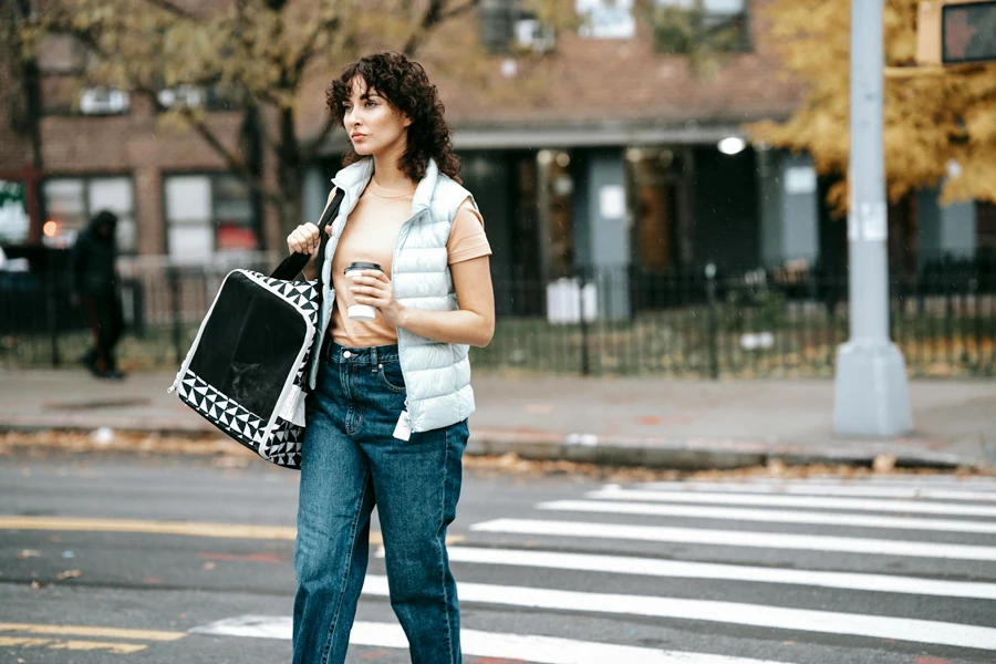 Woman with pet carrier and coffee to go crossing road