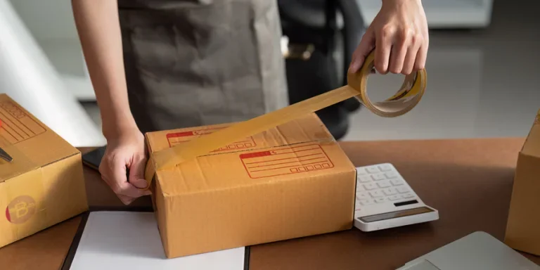 Young business entrepreneur sealing a box with tape. Preparing for shipping, Packing, online selling, e-commerce concept.